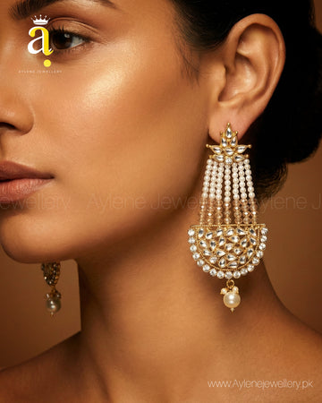 Close-up of a woman wearing a gold and pearl earring with Aylene Jewellery logo.